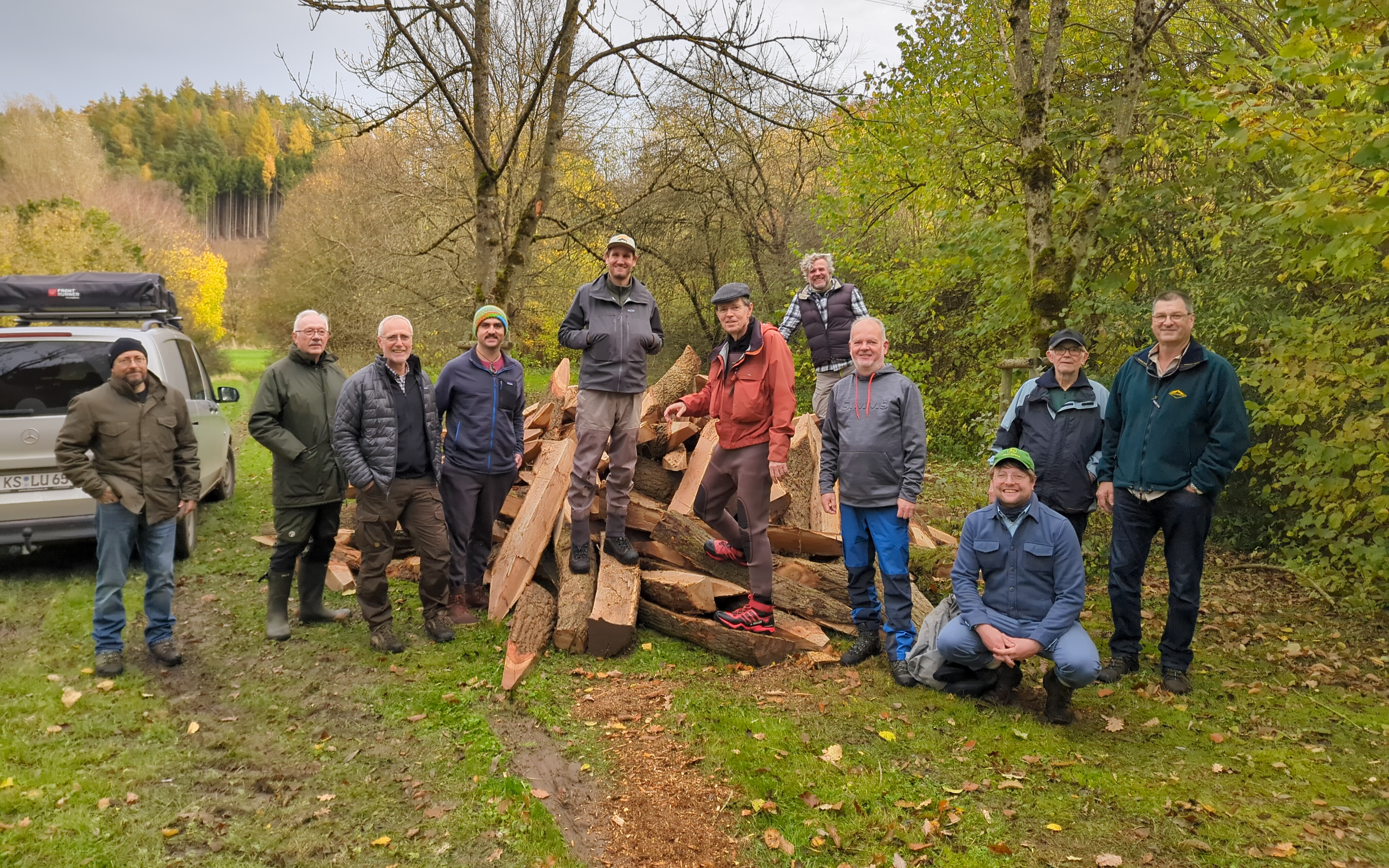 Eine Gruppe von Personen steht vor einem Haufen Eichenpfähle