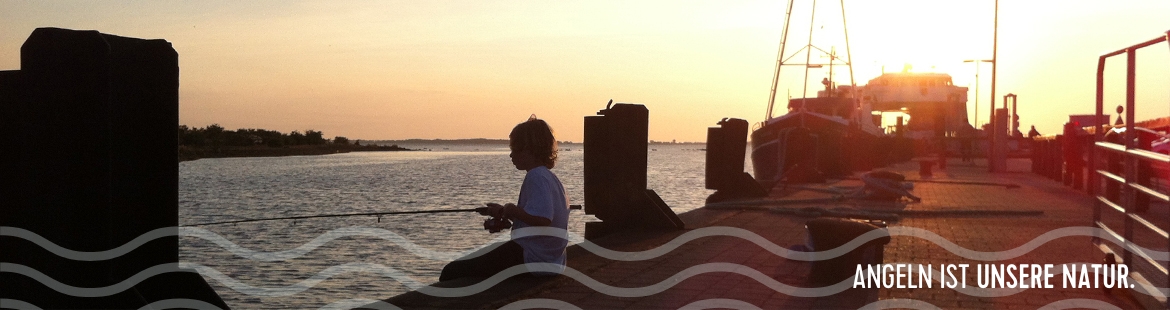 Ein Kind angelt in einem Hafen bei Sonnenuntergang